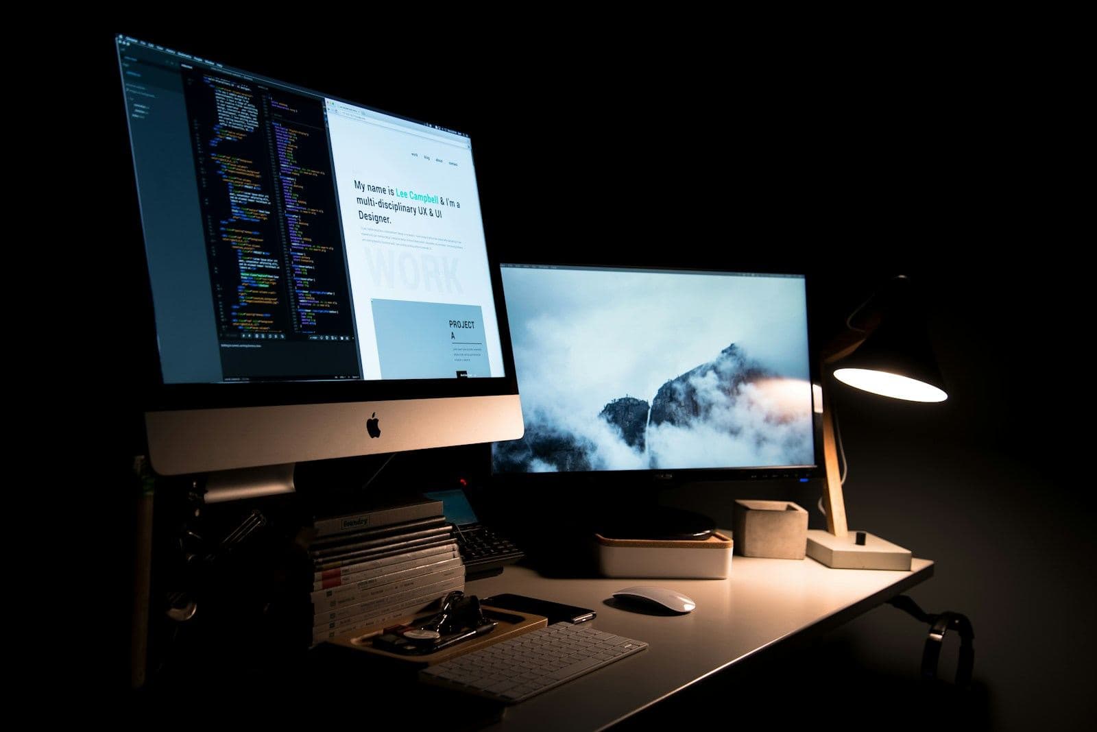 Desk lit by a lamp with code on screen at night